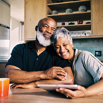Couple hugging while looking at tablet. Read about Gifts of Appreciated Securities Couple hugging while looking at tablet. Read about Gifts of Appreciated Securities